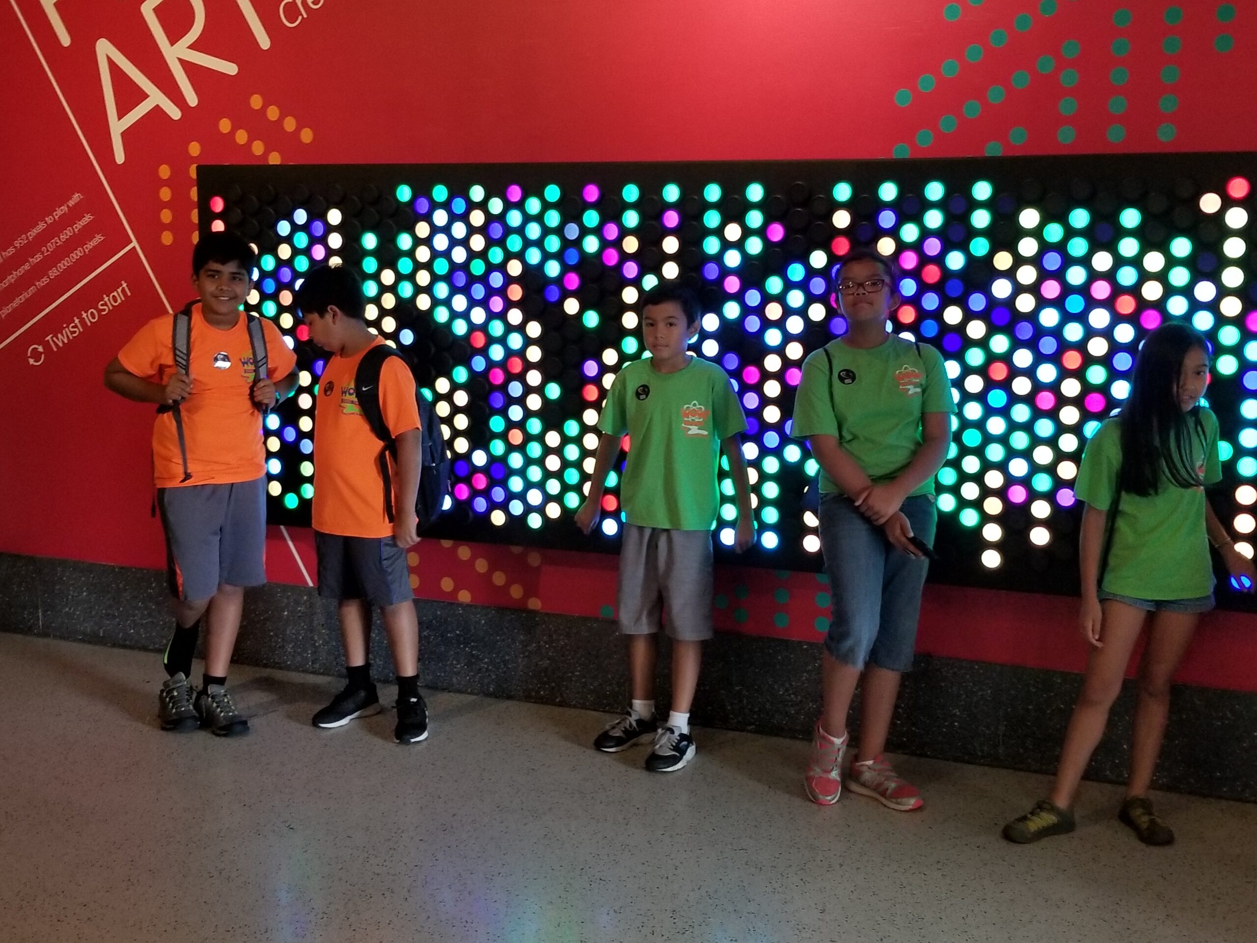 A group of people standing in front of a wall with lights.